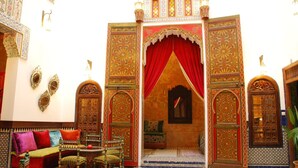 An ornate Moroccan interior with a red curtain, intricate wooden doors, and traditional furnishings. - Riad La Maison Verte (Fes)