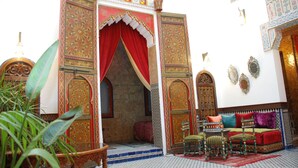 A traditional Moroccan interior with ornate doors, a seating area with cushions, and a patterned floor. - Riad La Maison Verte (Fes)