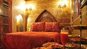 A luxurious room with a large bed, ornate wall decorations, and a buffet table with various dishes. - Riad La Maison Verte (Fes)
