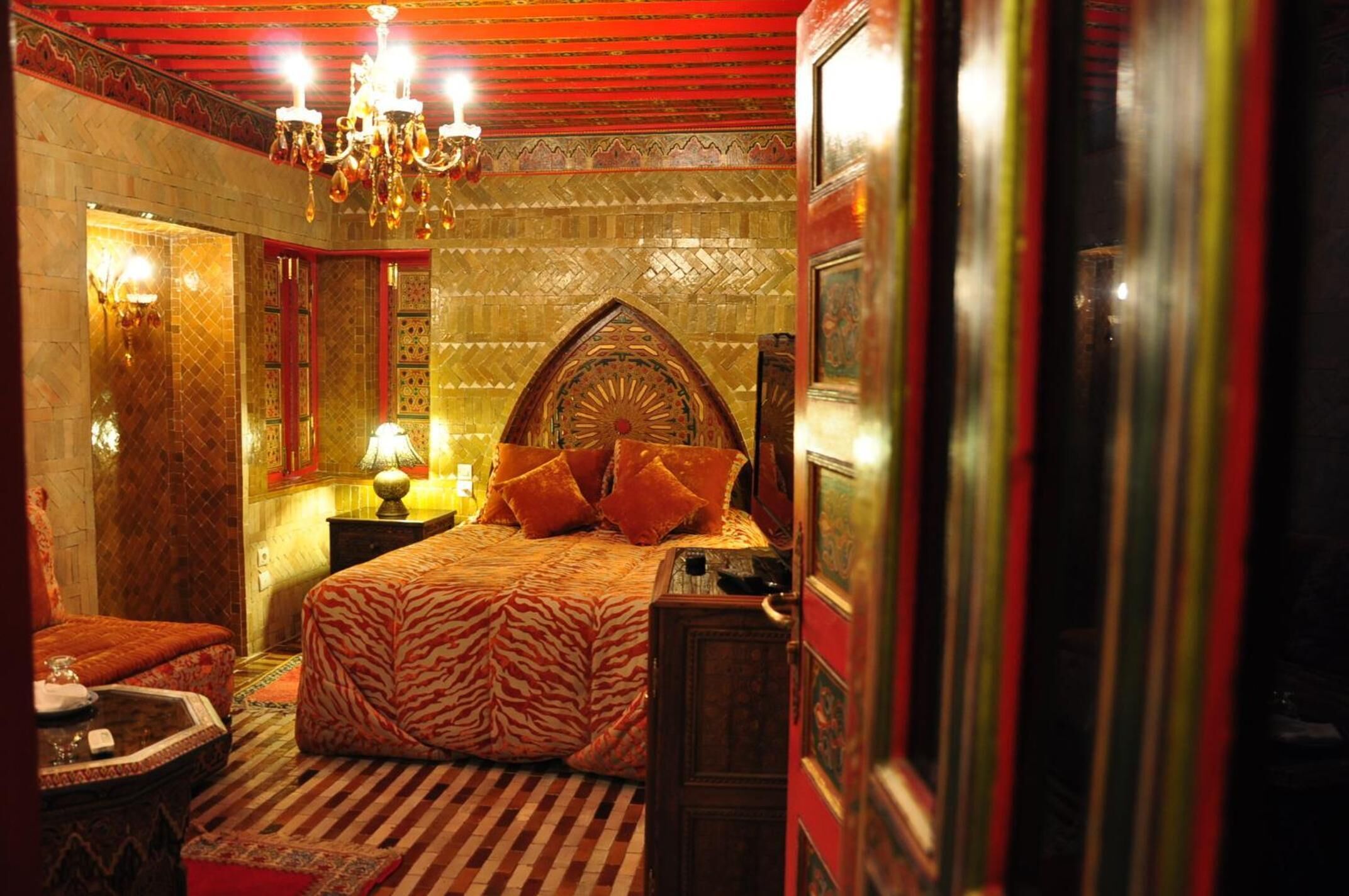 Quarto com cama, um lustre e um tapete estampado.