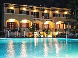 Un hotel con piscina, varios balcones y zonas de estar al aire libre.