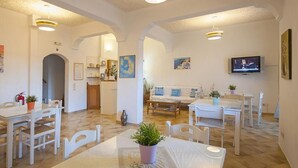 Un salón amplio con una mesa de comedor, sillas, un sofá y una televisión.