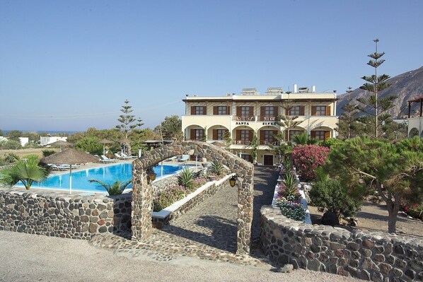 Un hotel con piscina, paredes de piedra y vistas al mar.