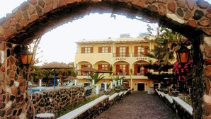 Un arco de piedra que conduce a un edificio con balcones y una zona de piscina.