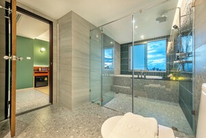 Un baño moderno con cabina de ducha de vidrio, una bañera grande y un inodoro con toalla.