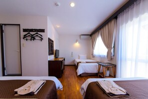 Una habitación de hotel con dos camas, un escritorio, una silla, un televisor y un armario.