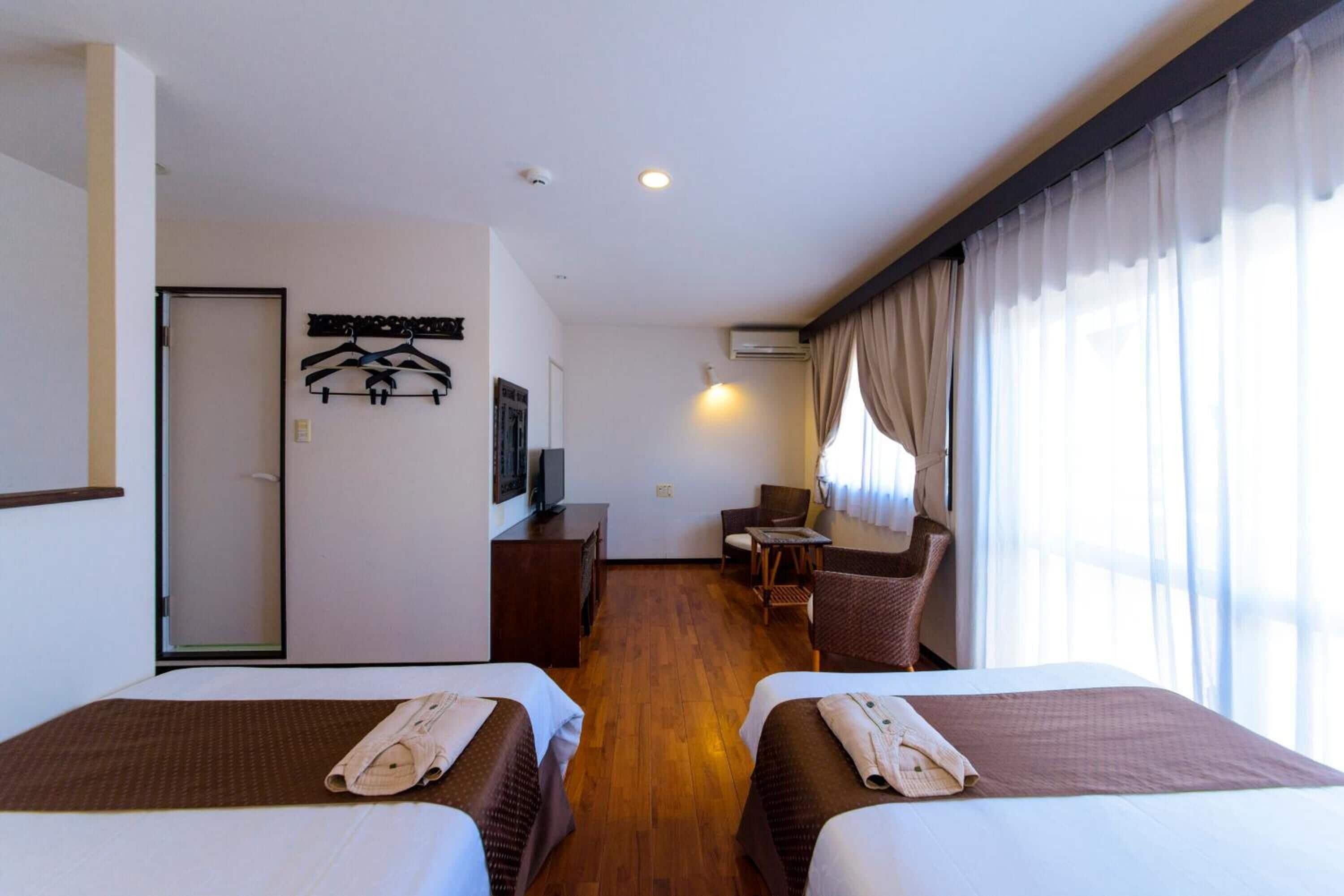 Une chambre d’hôtel avec deux lits, un bureau, une chaise et une petite table.