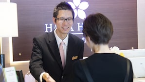Un mostrador de recepción de hotel con una placa de identificación y un logotipo floral en la pared de fondo.