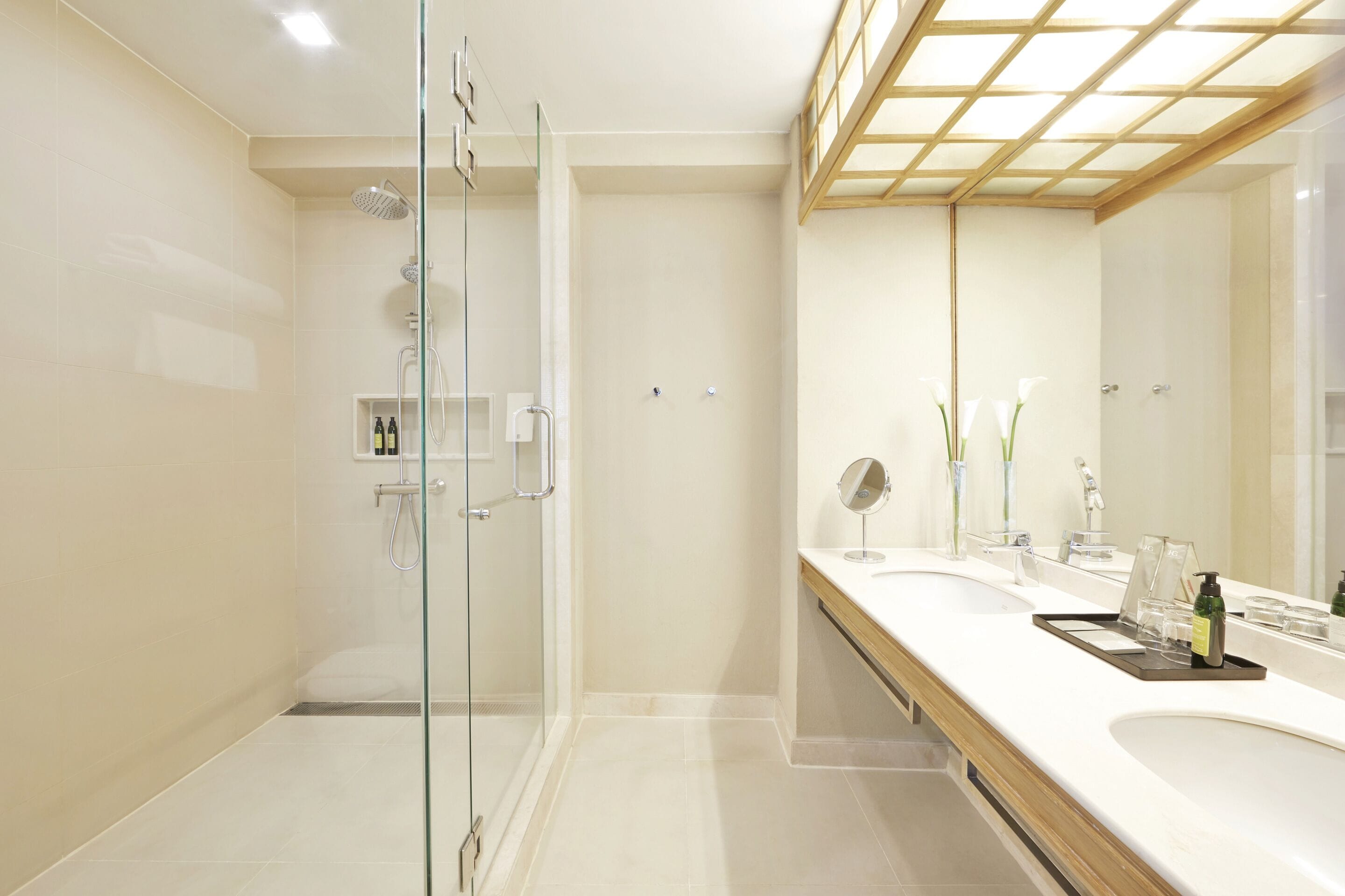 Un baño moderno con cabina de ducha de vidrio, un espejo grande y un tocador con lavamanos y encimera.