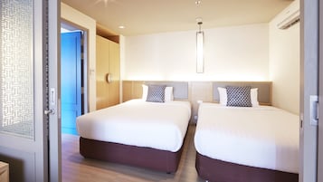 A hotel room with two beds, a modern light fixture, and a door with a geometric pattern.