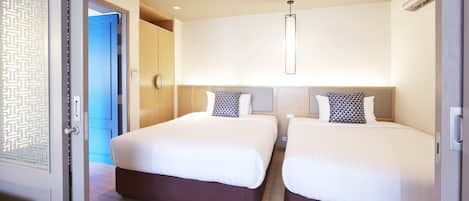 A hotel room with two beds, a modern light fixture, and a door with a geometric pattern.