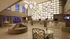 Een ruime lobby met een modern design, met een grote zithoek, een receptiebalie en een presentatiemuur met diverse objecten.