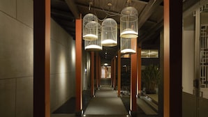 Een gang met hangende lampen en een trap op de achtergrond.