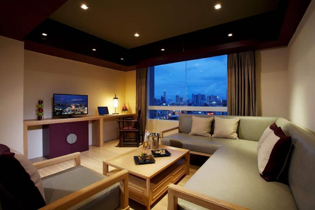 Habitación de hotel moderna con vista a la ciudad, un sofá, una mesa de comedor y un televisor.