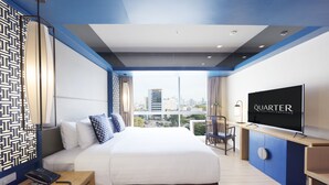Een moderne hotelkamer met een groot bed, een bureau, een stoel, een televisie en uitzicht op de stad.