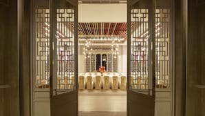 Een klassiek interieur met een receptie, een centraal bloemarrangement en een zithoek met stoelen.