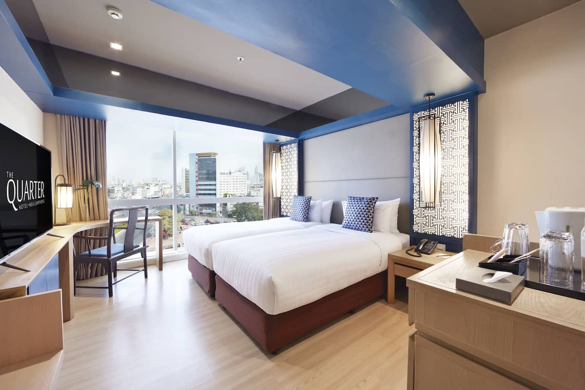 A modern hotel room with a large bed, a desk, and a city view.