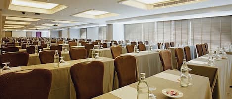 A large conference room with multiple tables and chairs, equipped with water bottles and glasses.