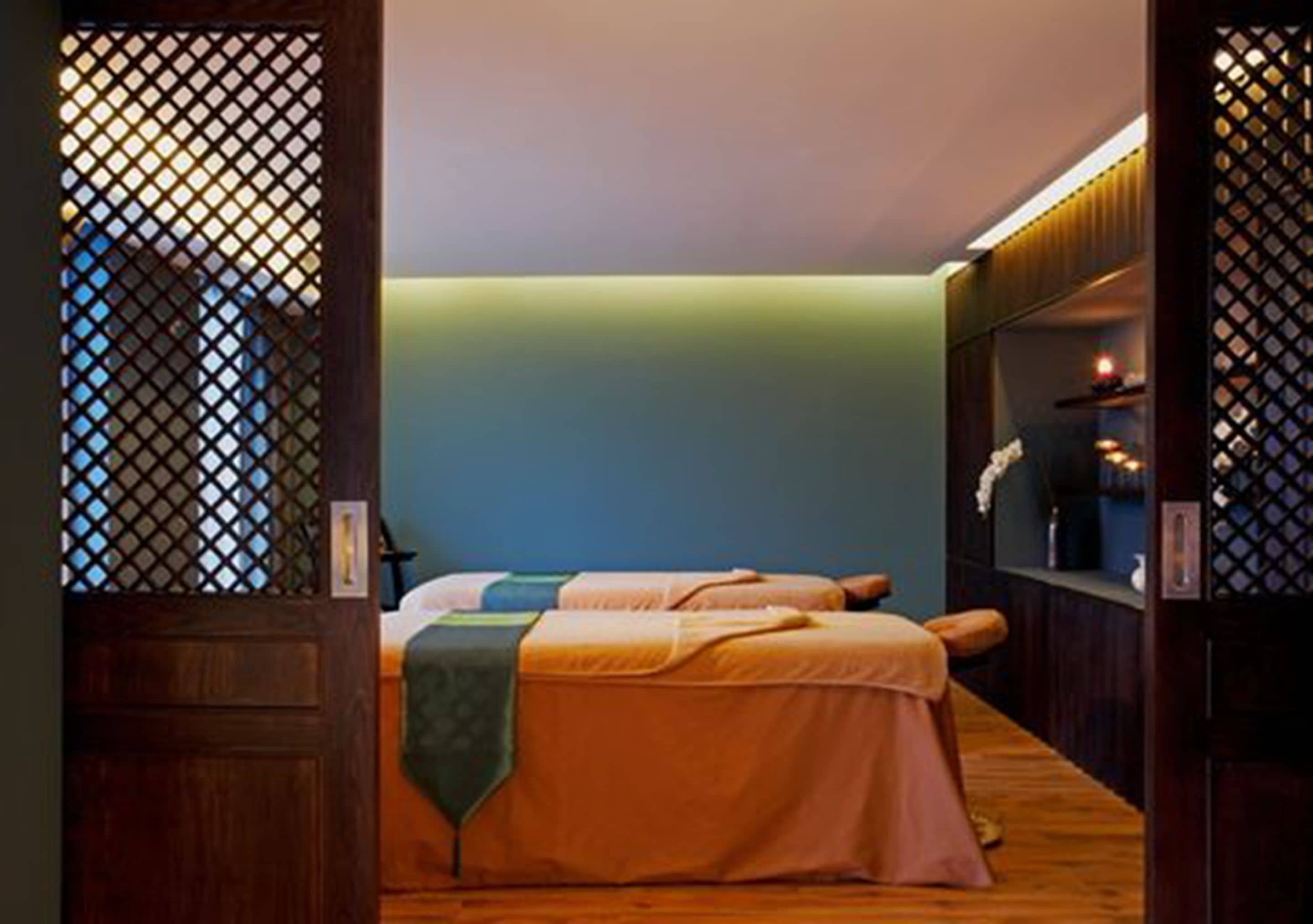 Una habitación con cama, piso de madera y una estantería con objetos decorativos.
