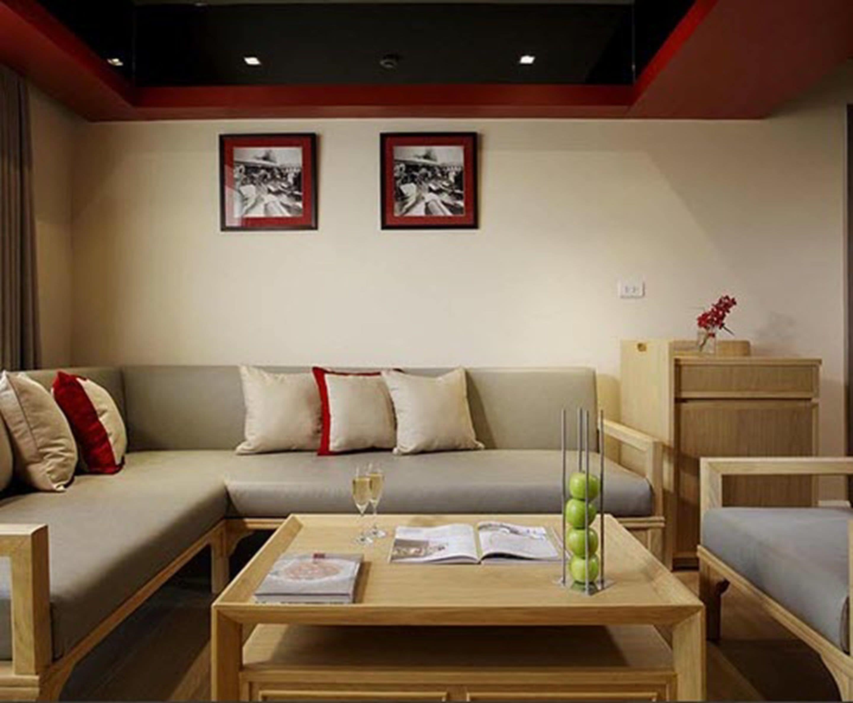 Una sala de estar moderna con un sofá, una mesa de centro con libros y una copa de vino, y dos cuadros en la pared.