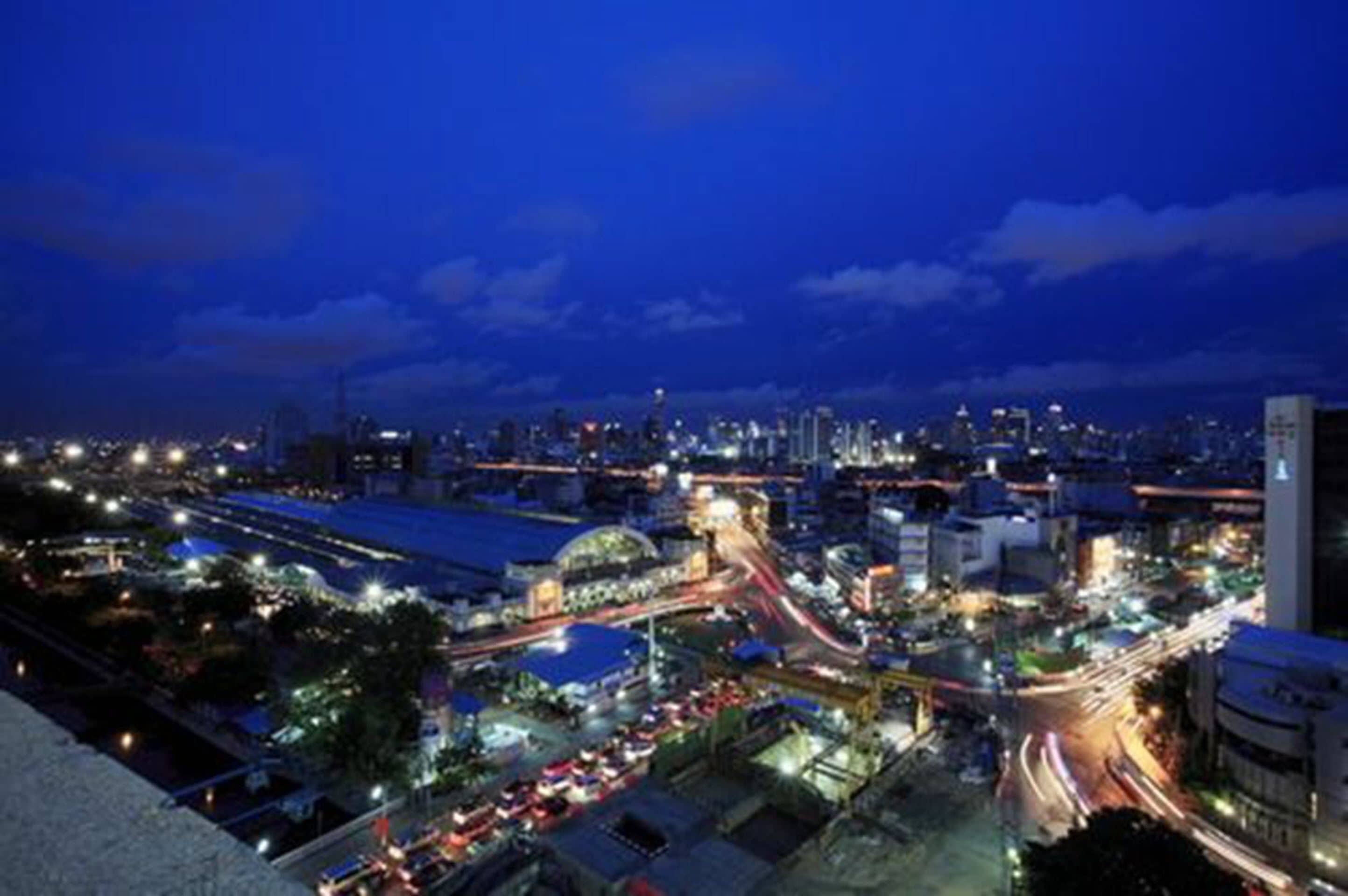 A nighttime cityscape with illuminated buildings and busy roads.