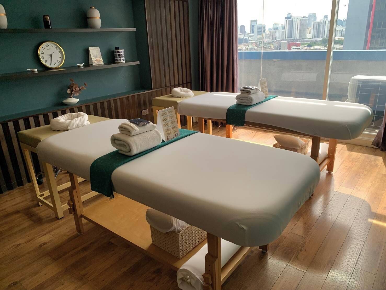 A room with two massage tables, a clock, and a city view.