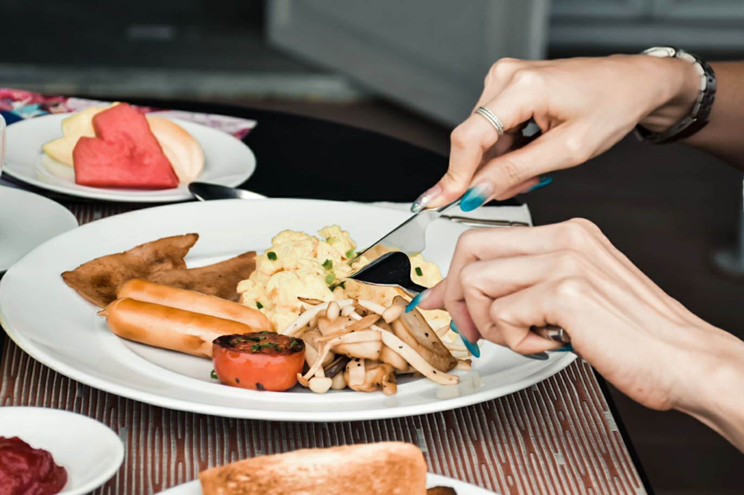A person cutting food on a plate.