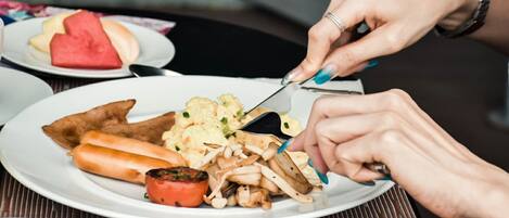 A person cutting food on a plate.