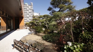 Een traditionele Japanse tuin met een houten bank, stenen en verschillende planten.