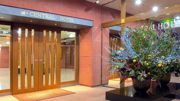 De ingang van Hotel Central met een houten deur en een grote bloemenpresentatie ervoor.