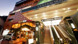 Het uiterlijk van Hotel Central, met een zichtbare ingang, roltrap en een geparkeerde auto.