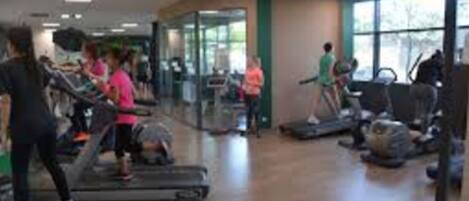 Un gimnasio con cintas de correr, bicicletas estáticas y máquinas de pesas.