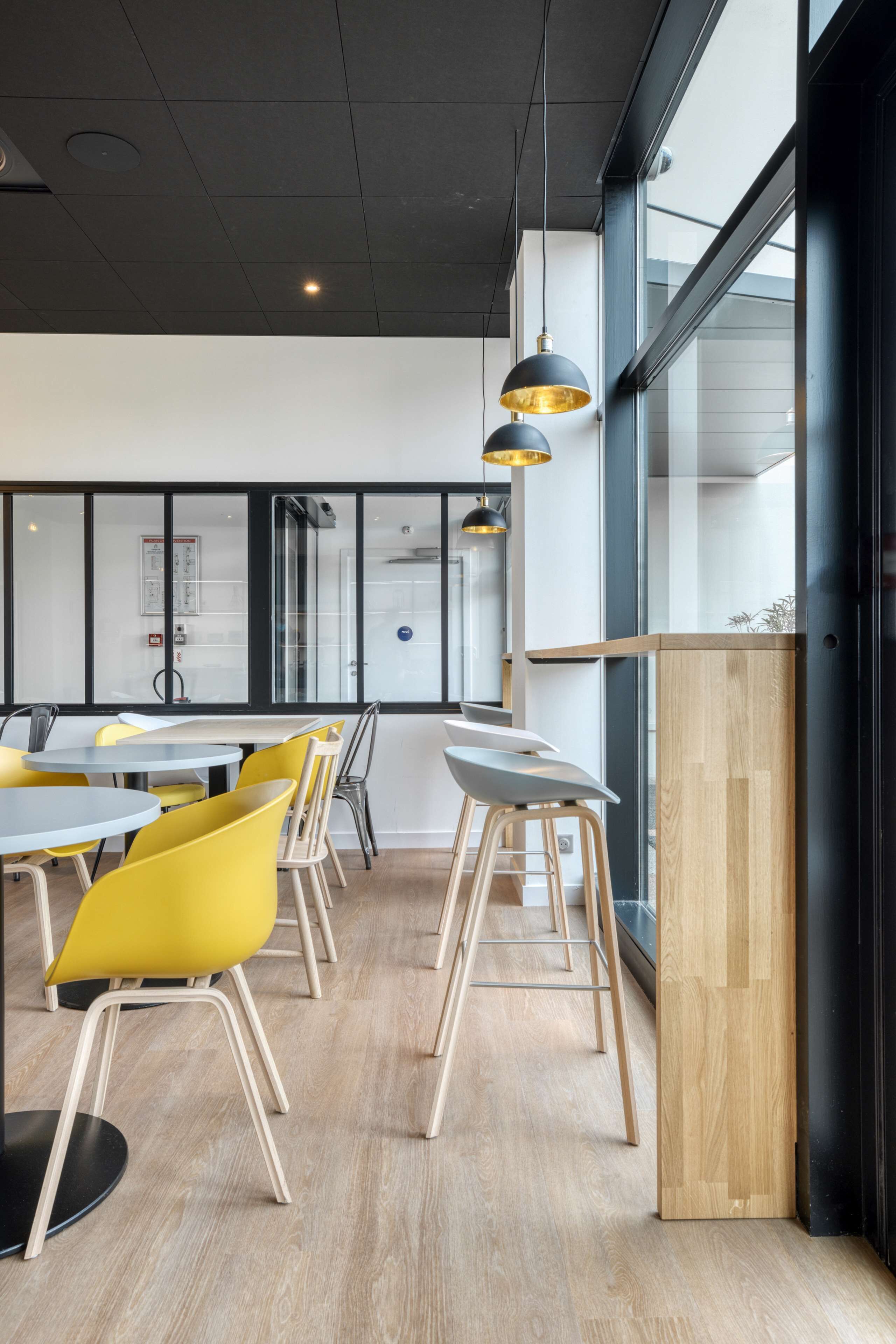 Un salón de conferencias moderno con mesas redondas, sillas amarillas e iluminación colgante.
