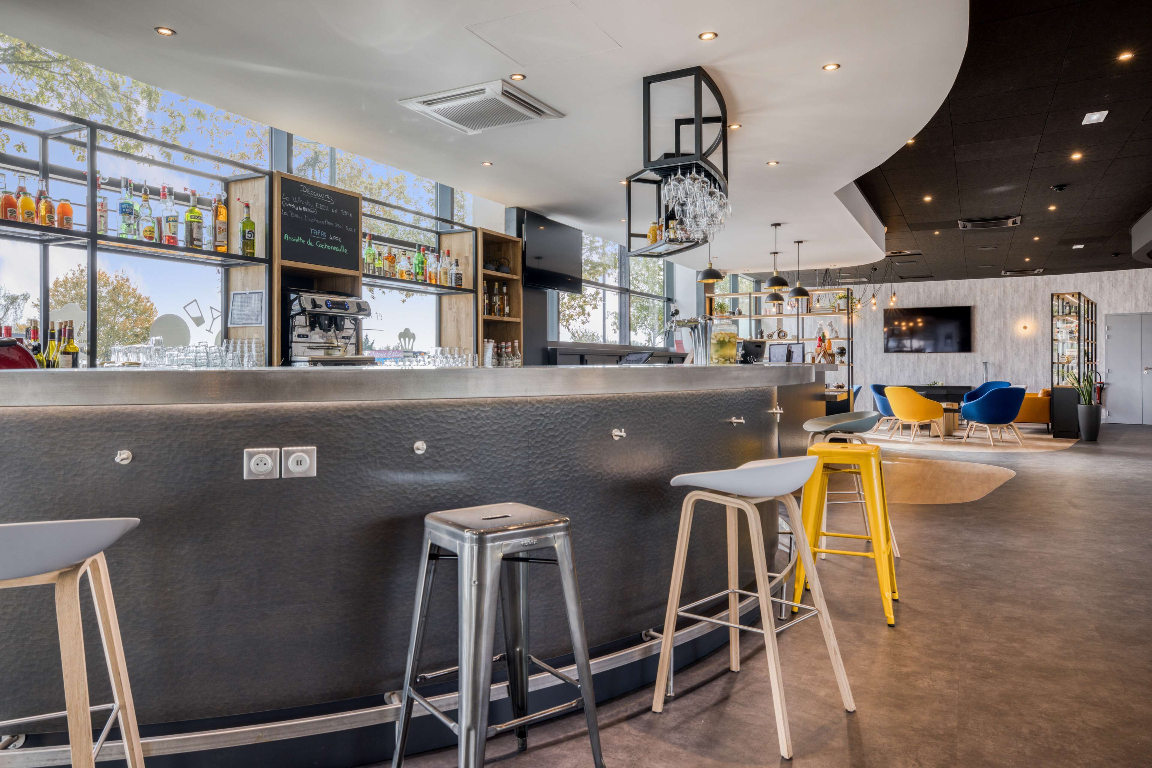 A modern bar area with a bar counter, stools, and a seating area with chairs and tables.