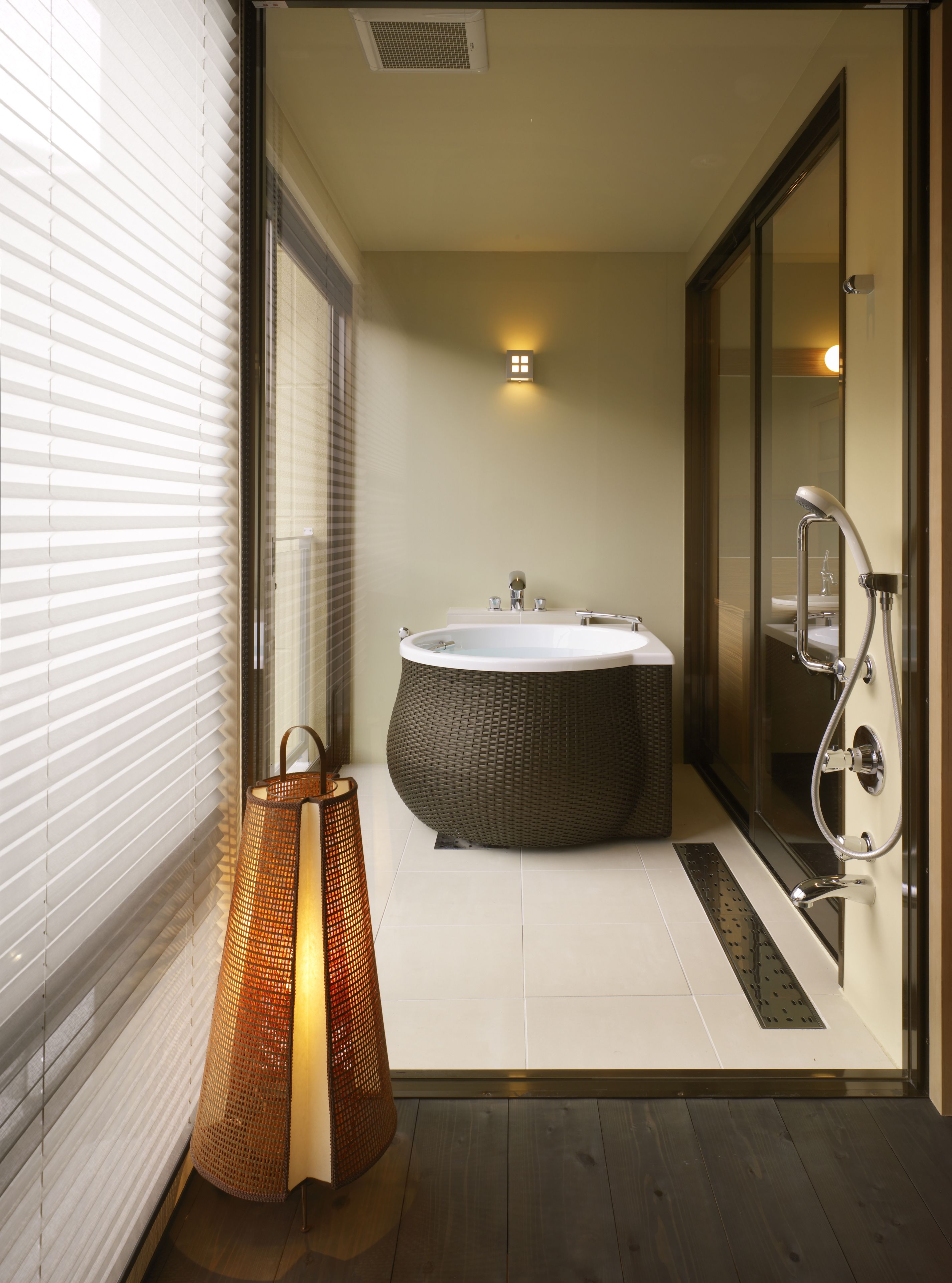 A modern bathroom with a large bathtub, a glass shower enclosure, and a wicker chair.