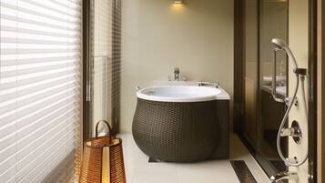 Une salle de bain moderne avec une grande baignoire, une cabine de douche en verre et un fauteuil en osier.