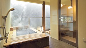 Un baño moderno con una bañera de hidromasaje con recinto de vidrio, zona de ducha y un amplio ventanal con vistas a las montañas.