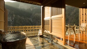Un jacuzzi en una terraza de piedra con vistas a montañas.