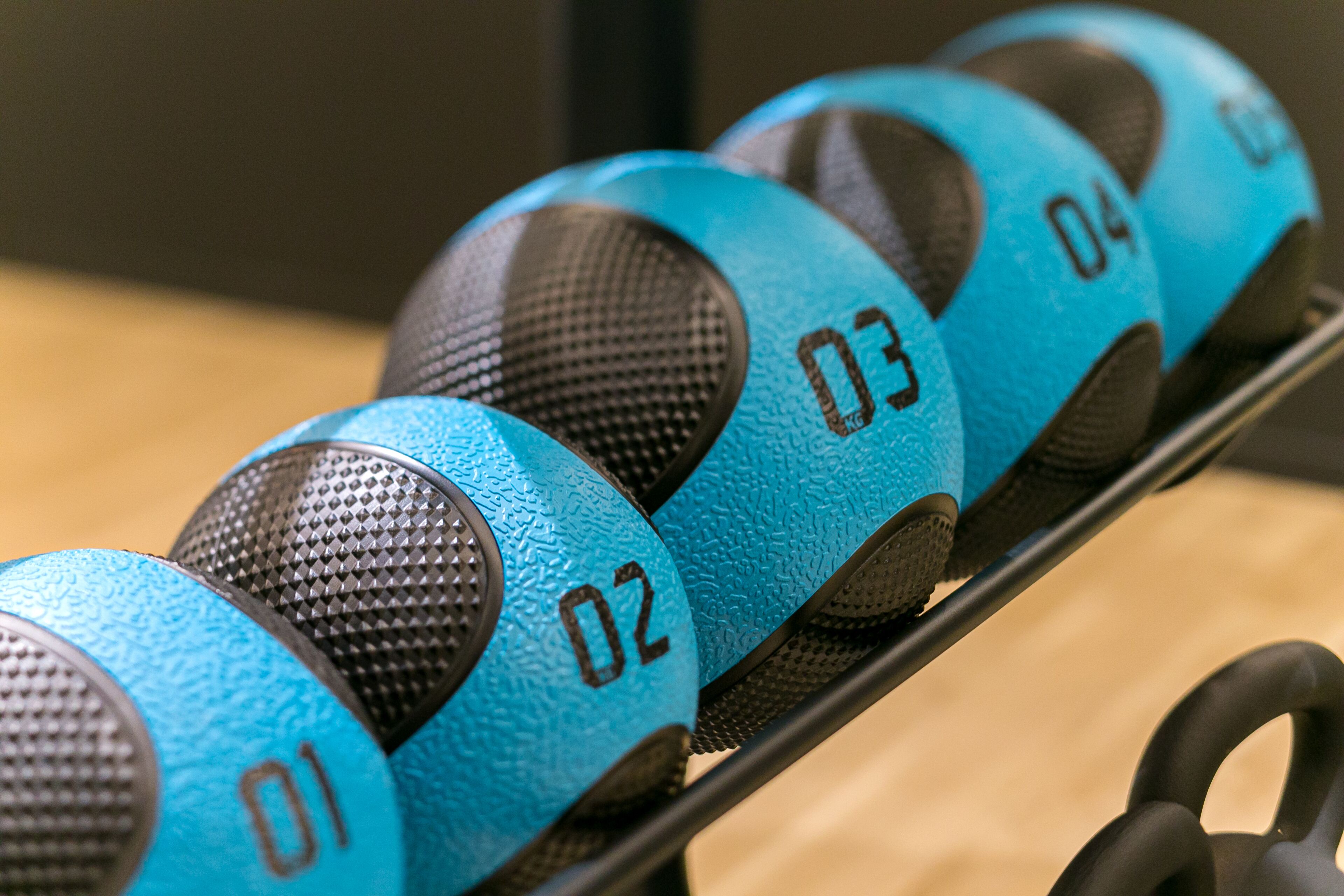 A set of blue and black exercise balls with numbers 01 to 04 on a rack.