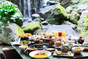 A breakfast buffet with a variety of dishes, including eggs, meats, and fruits, set against a backdrop of a waterfall and greenery. - Hotel New Nagasaki (Nagasaki)