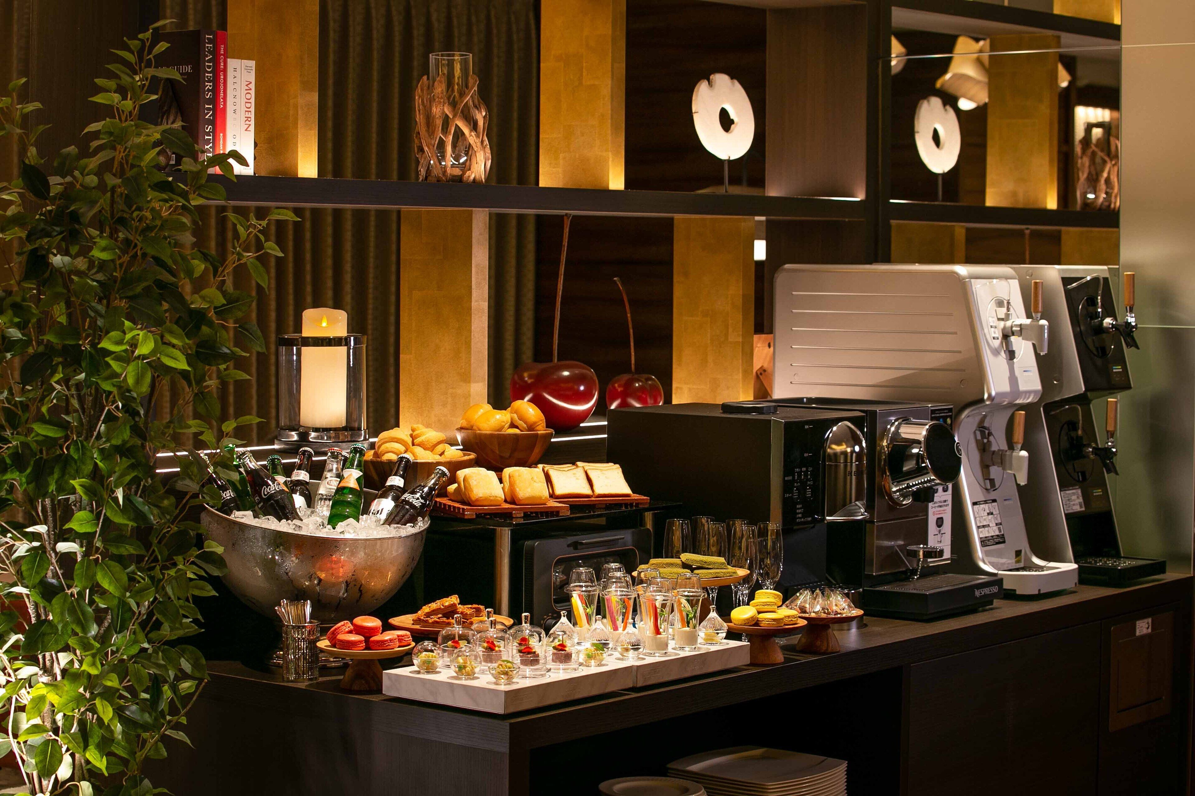 A buffet setup with a variety of food items, a coffee machine, and a large bowl of ice.