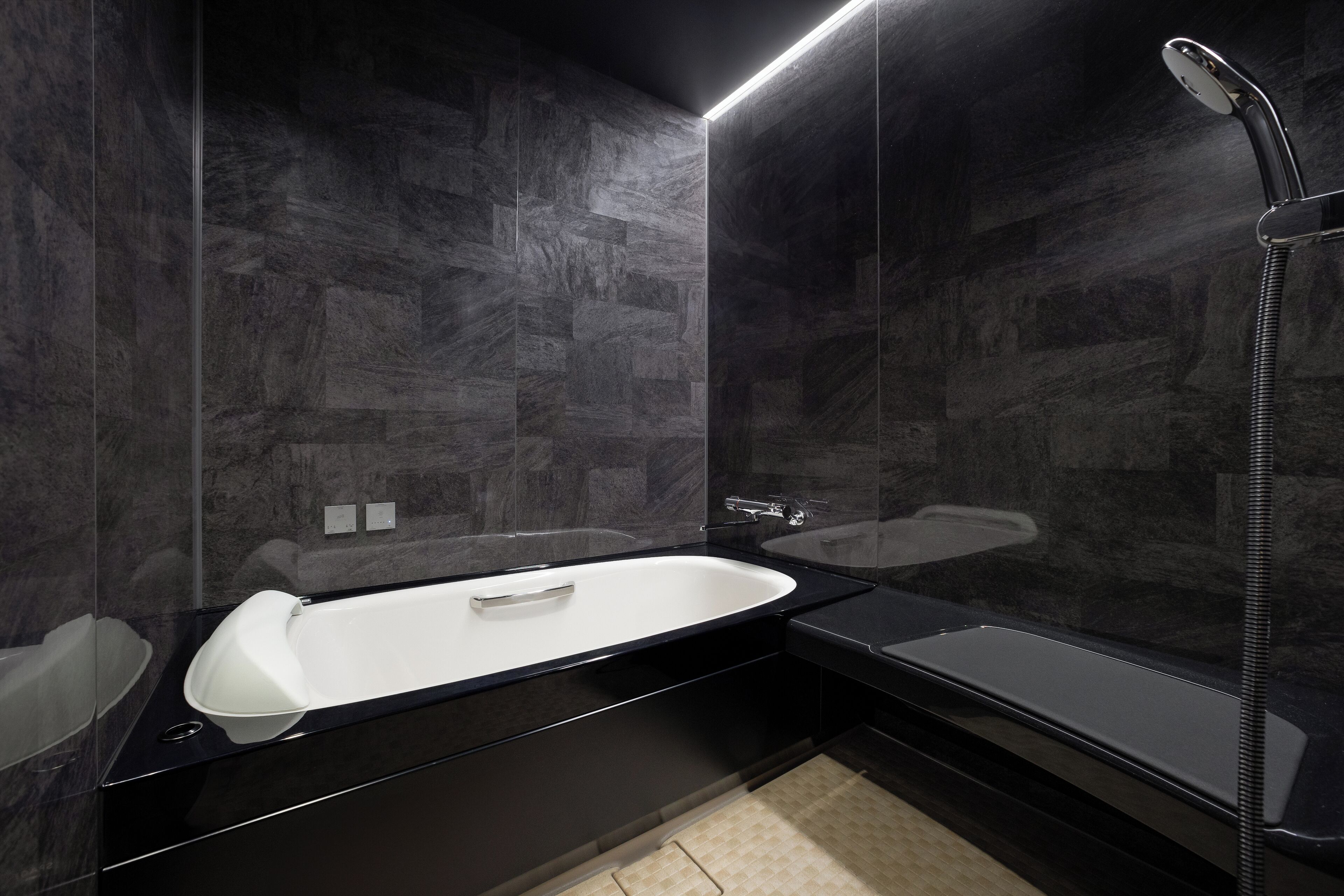 A modern bathroom with a black bathtub, a separate shower area, and dark marble walls.