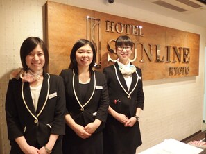 Tres personas frente a un cartel que dice "HOTEL SUNLINE KYOTO".