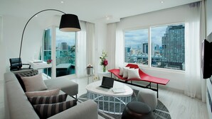 Un salon moderne avec vue sur la ville, un ordinateur portable posé sur une table basse et un banc rouge.