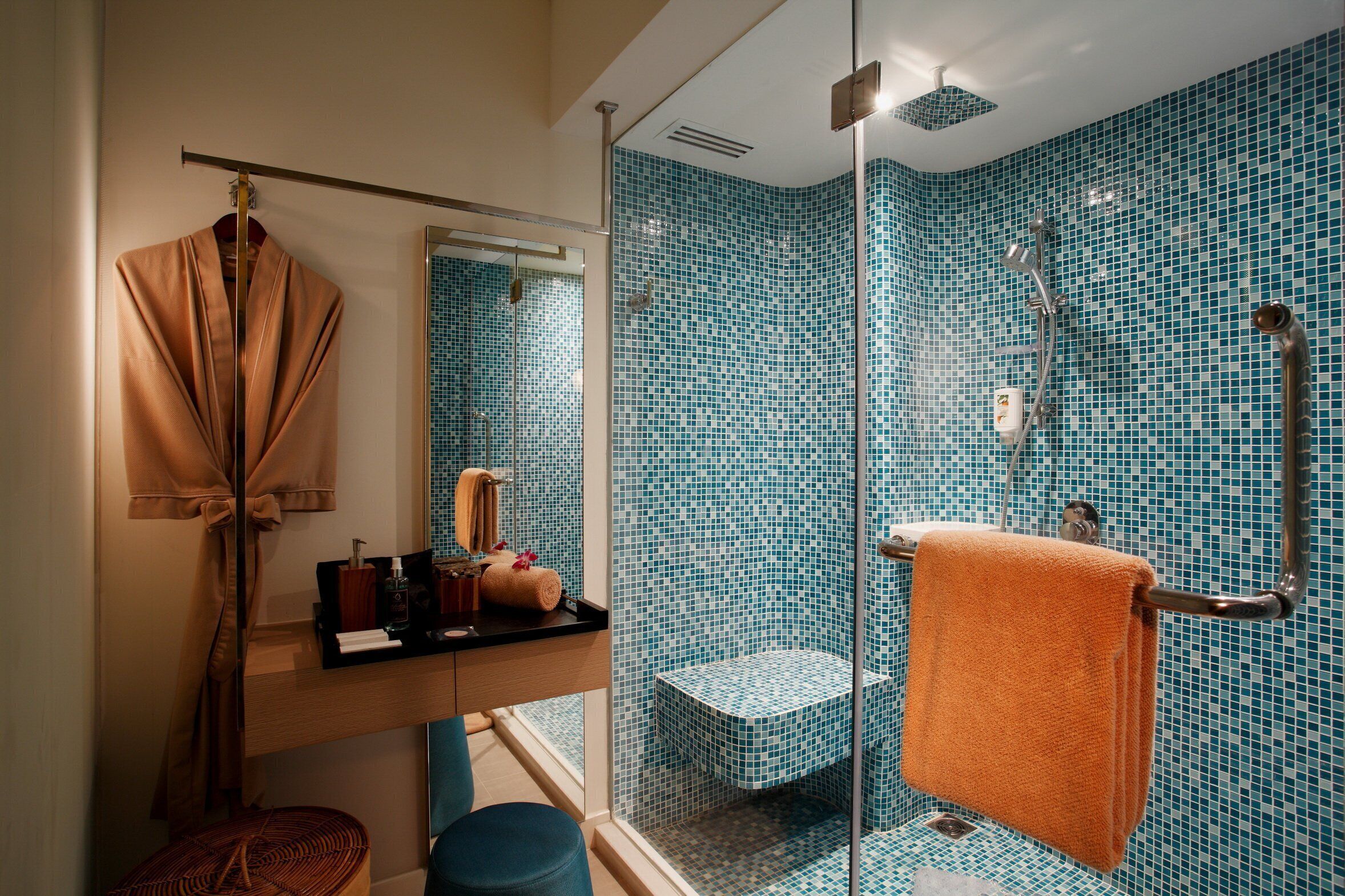 A bathroom with a glass shower enclosure, a wooden vanity, and a towel rack.