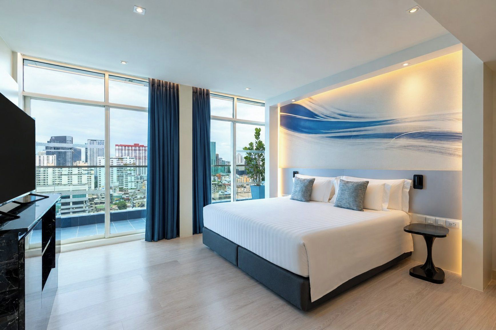 Ein modernes Hotelzimmer mit einem großen Bett, einem Schreibtisch und Blick auf die Stadt.