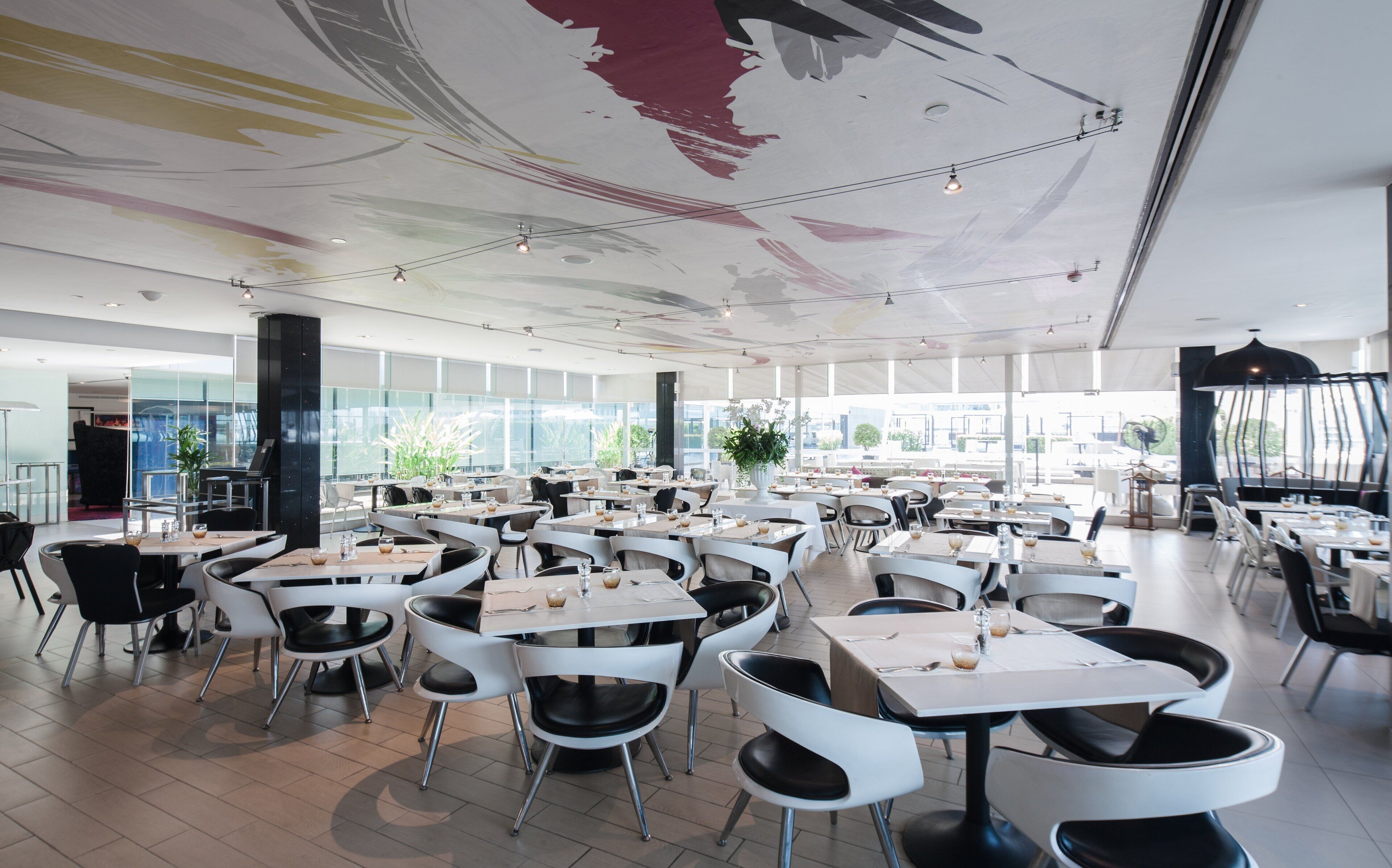 A spacious restaurant with high ceilings, modern chairs, and tables arranged for dining.