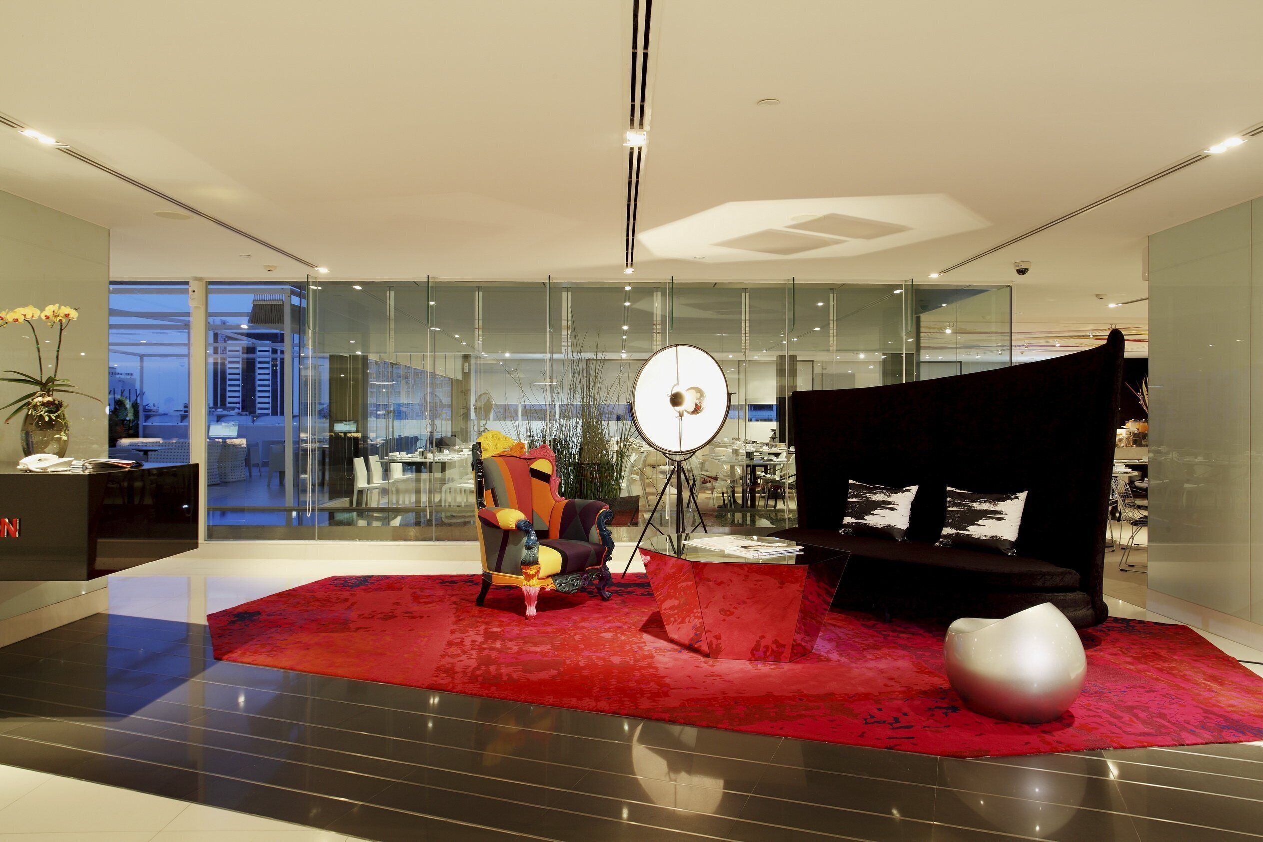 A modern living room with a red carpet, a black sofa, and a colorful armchair.