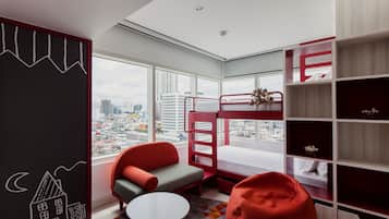 Enjoy city views from the large windows in this cozy room featuring a bunk bed, comfortable chair, and bookshelf.