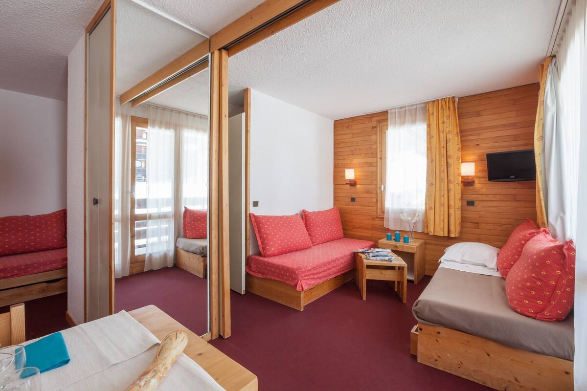 Une pièce comprenant un lit, un canapé, une petite table et un miroir.